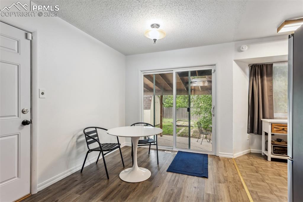 Image 4 of 20: Unfurnished dining area featuring baseboards, a textured ceiling, and wood