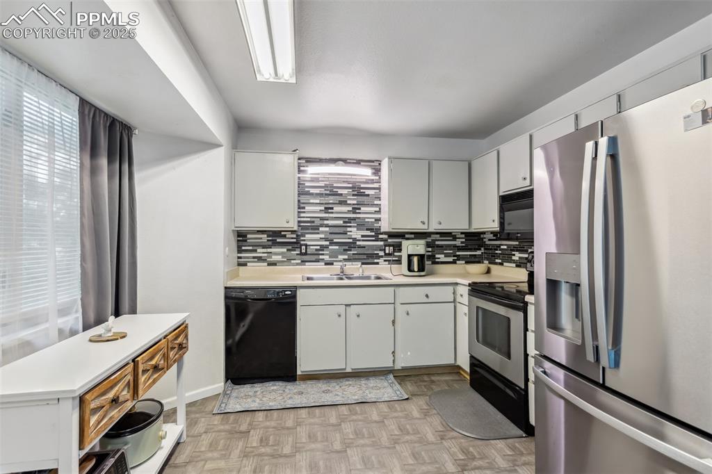 Image 6 of 20: Kitchen featuring black appliances, a sink, light countertops, and healthy