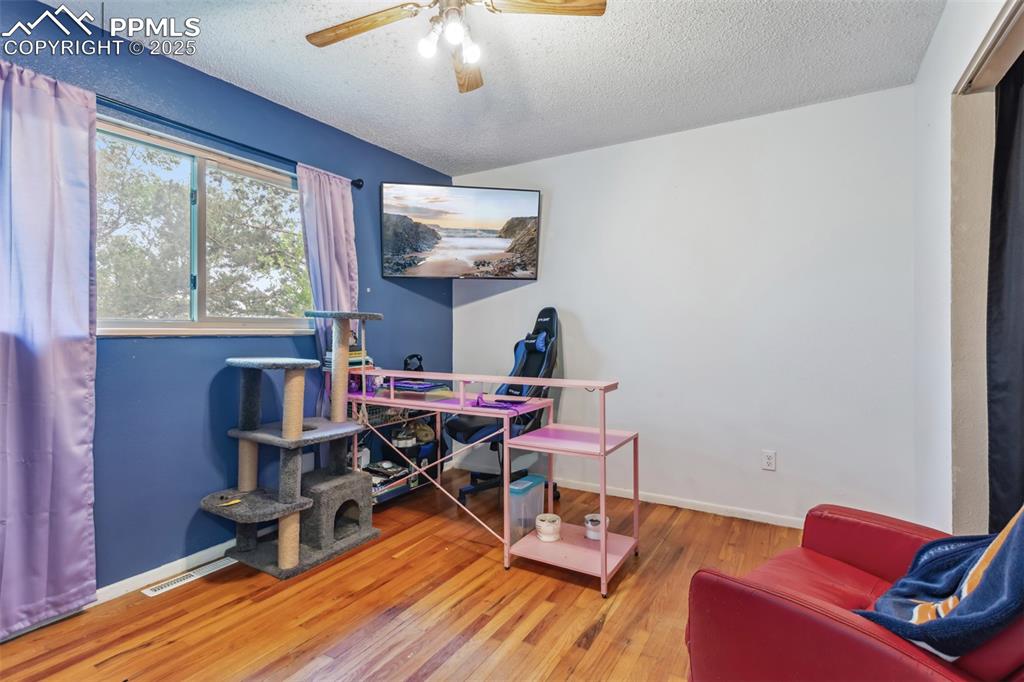Image 9 of 20: Home office with a textured ceiling, a ceiling fan, wood finished floors, a