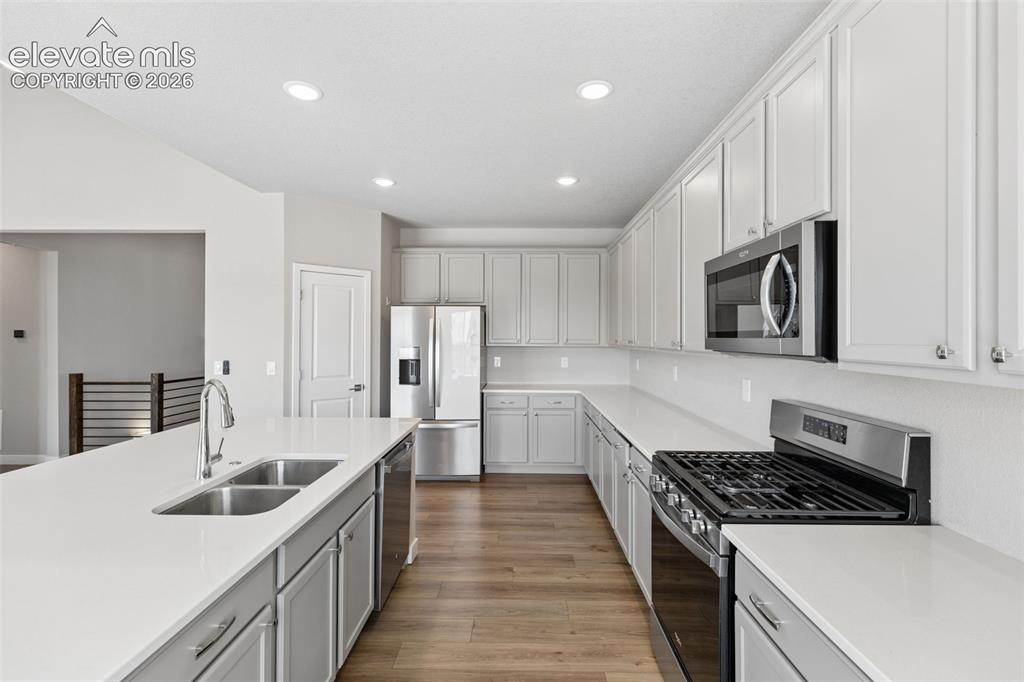 Image 11 of 40: Kitchen featuring white shaker-style cabinetry, solid-surface countertops, 