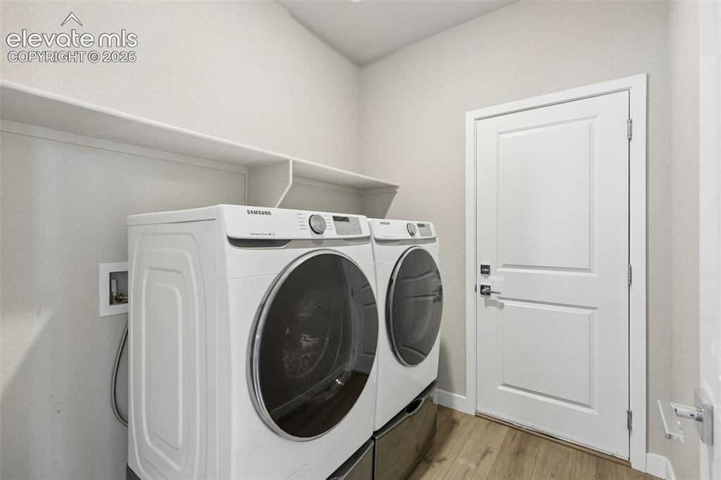 Image 12 of 40: Utility room featuring wood-finish flooring, a white paneled door, and buil