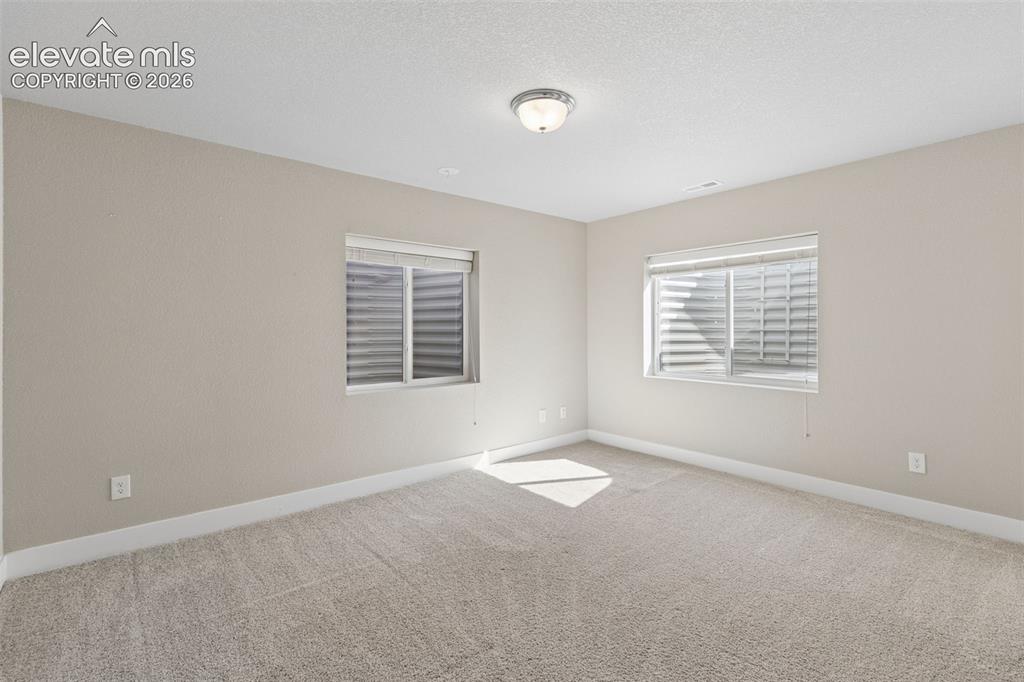 Image 23 of 40: Neutral-toned room featuring wall-to-wall carpeting, two egress windows wit