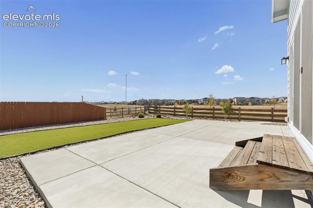 Image 27 of 40: Concrete patio with wooden steps, synthetic turf lawn, wood-style privacy f