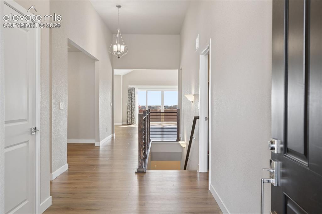 Image 3 of 40: Entryway featuring wood-finish flooring, high ceilings, geometric pendant l