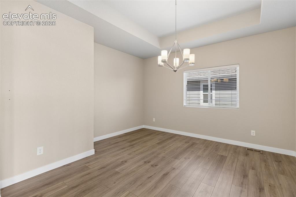 Image 4 of 40: Tray ceiling featuring a multi-arm polished nickel chandelier, wood-finish