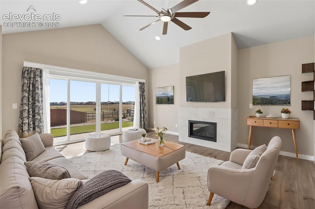 Image 6 of 40: Vaulted ceilings, large sliding glass doors, fireplace with light-toned mas