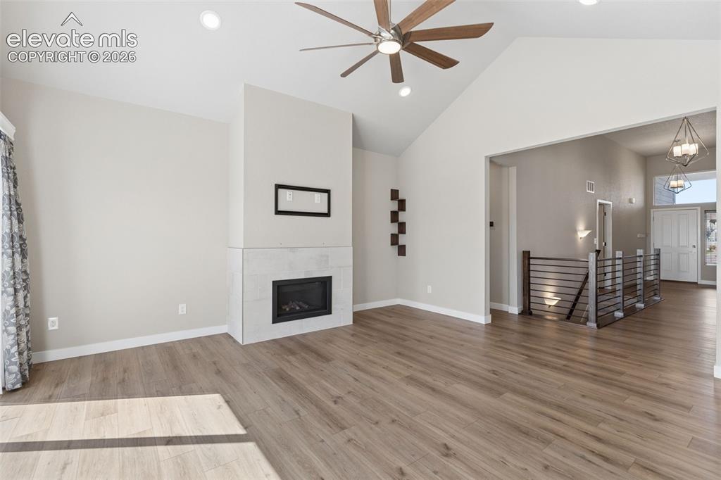 Image 7 of 40: Vaulted ceiling, stone-surround fireplace, wood-finish flooring, ceiling fa