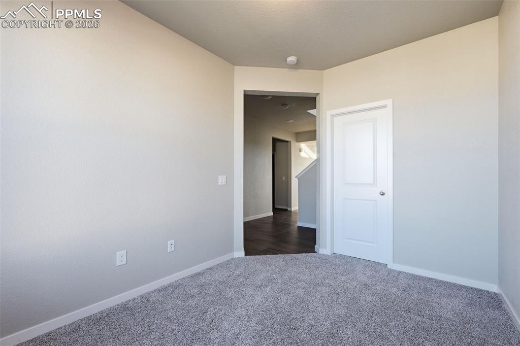 Image 17 of 48: Unfurnished room featuring baseboards and dark colored carpet