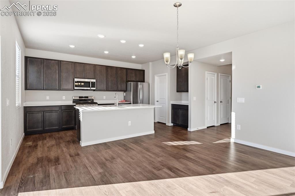 Image 3 of 48: Kitchen featuring dark wood finish cabinets, suspended lighting, stainless 