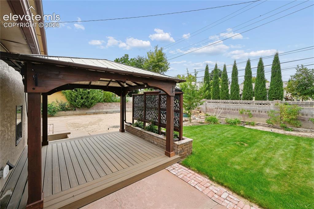Image 45 of 50: Beautifully Landscaped Backyard with Covered Deck