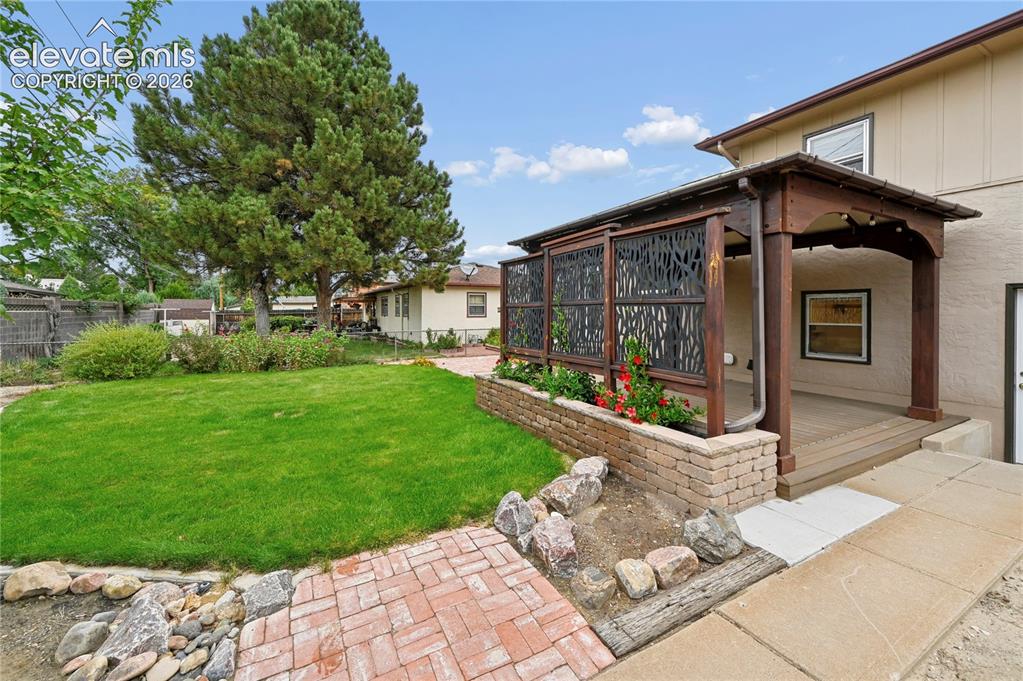 Image 46 of 50: Beautifully Landscaped Backyard with Covered Deck