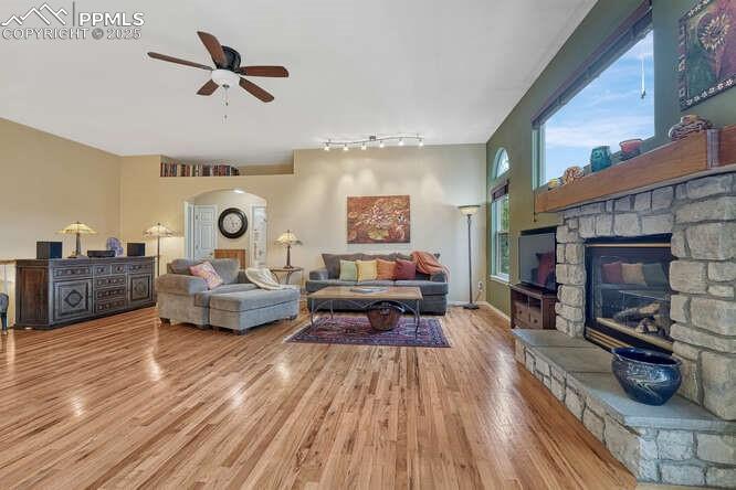 Image 10 of 48: Living area with wood floors, a stone fireplace