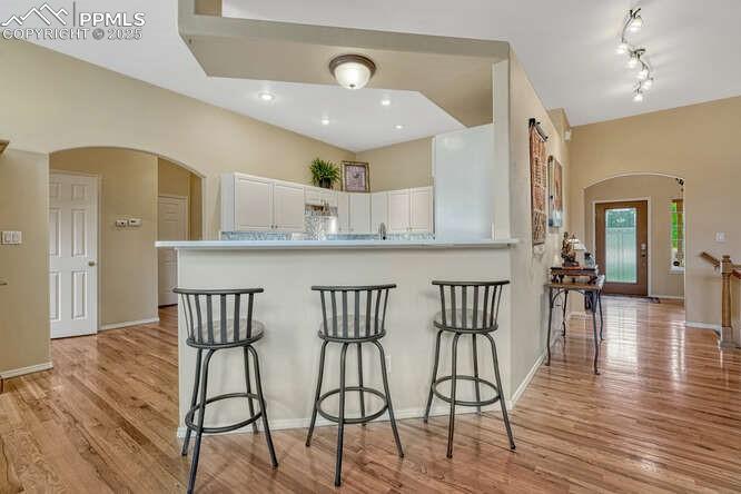 Image 14 of 48: Kitchen with arched walkways, white cabinetry, a kitchen breakfast bar