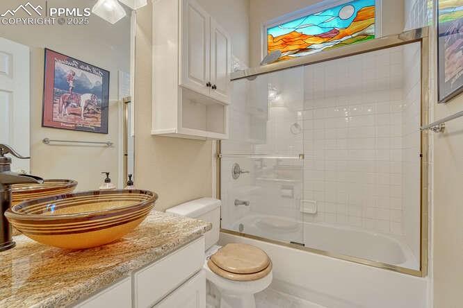 Image 20 of 48: Full bath featuring vanity and shower / bath combination with glass door