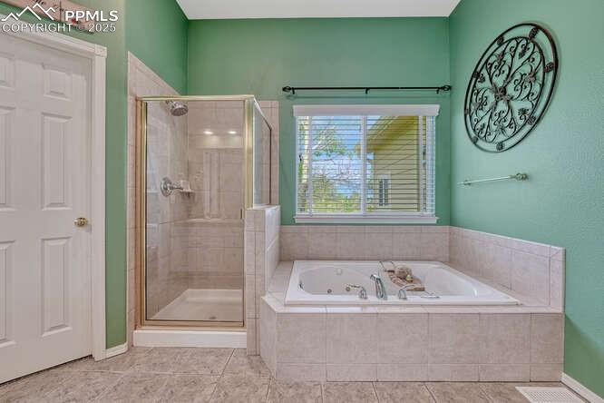Image 29 of 48: Bathroom featuring a stall shower, a bath, and dual vanities