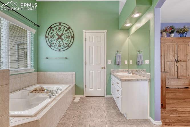 Image 30 of 48: Bathroom featuring a stall shower, a bath, and dual vanities