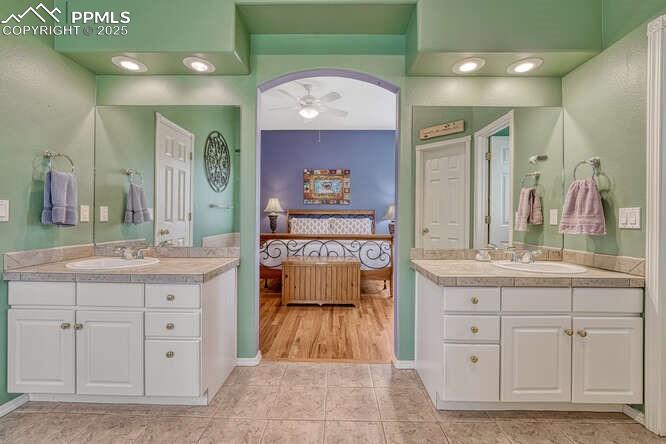 Image 31 of 48: Bathroom featuring a stall shower, a bath, and dual vanities