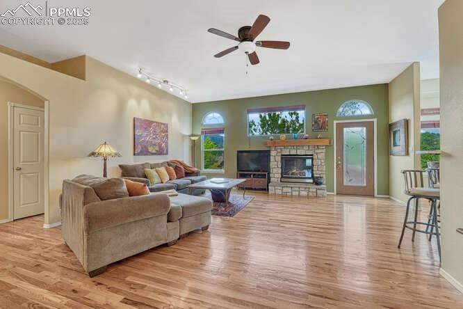 Image 9 of 48: Living area with arched walkways, ceiling fan, wood floors