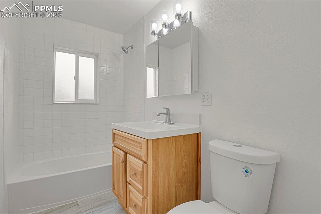 Image 14 of 29: Renovated bathroom with new tile flooring, lighting, vanity, and plumbing f