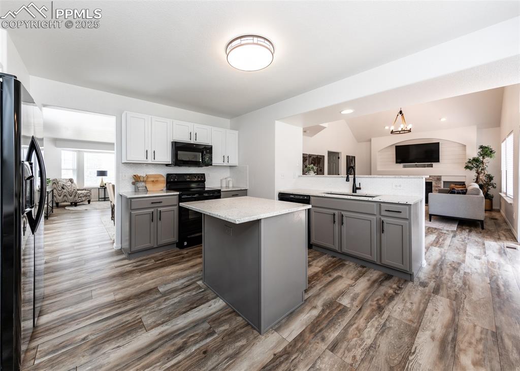 Image 10 of 50: Kitchen with black appliances, gray cabinets, a sink, open floor plan, and