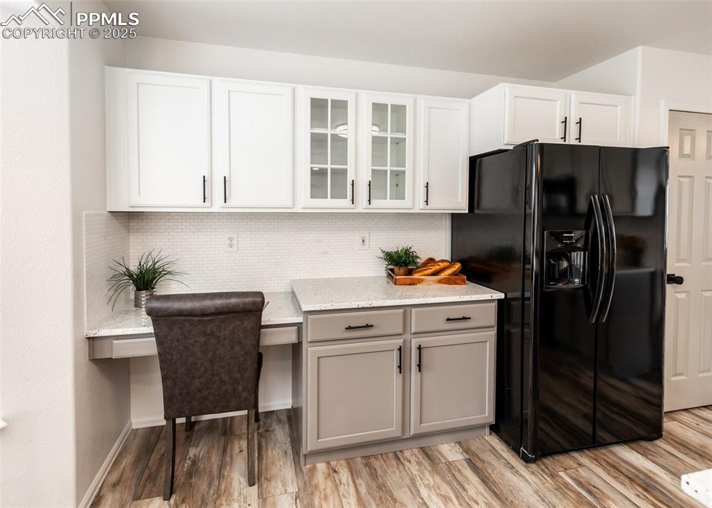 Image 11 of 50: Kitchen featuring black refrigerator with ice dispenser, light stone counte
