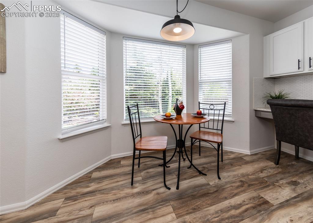 Image 13 of 50: Dining room with wood finished floors, baseboards, and plenty of natural li