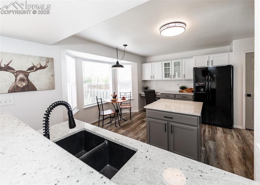 Image 15 of 50: Kitchen with black fridge with ice dispenser, a sink, dark wood finished fl