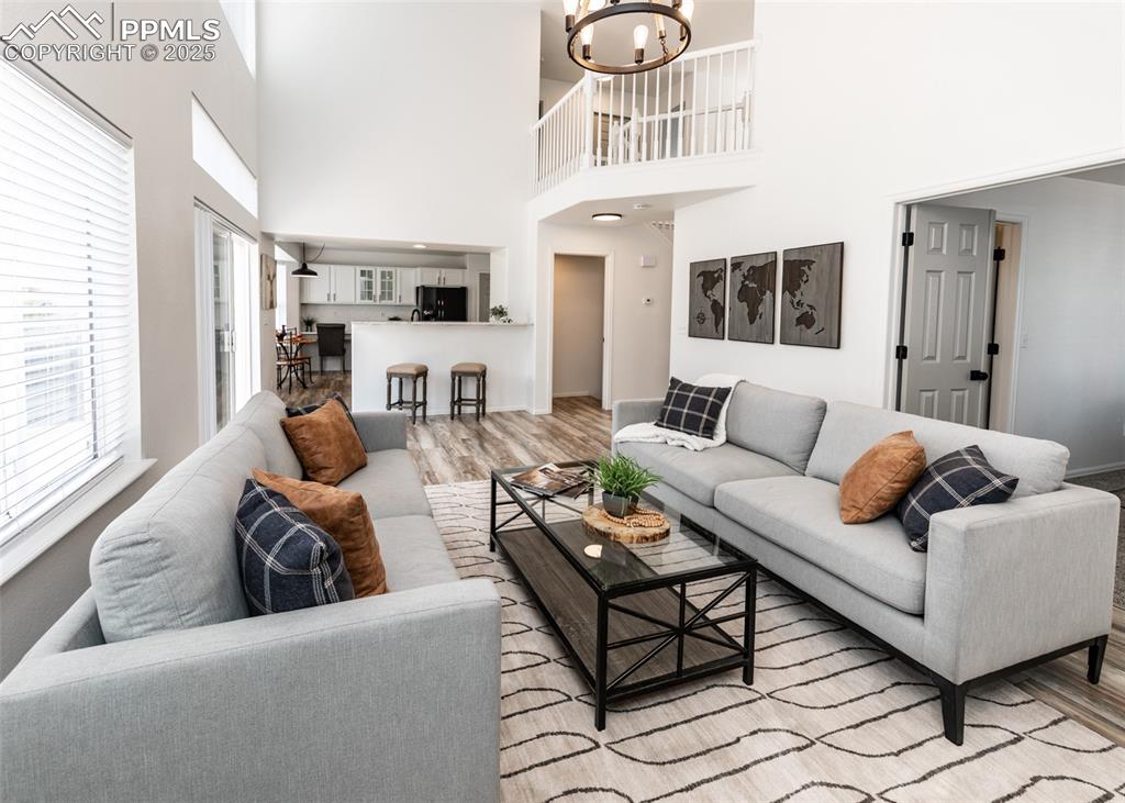 Image 17 of 50: Living room featuring a chandelier, light wood-style flooring, and a high c