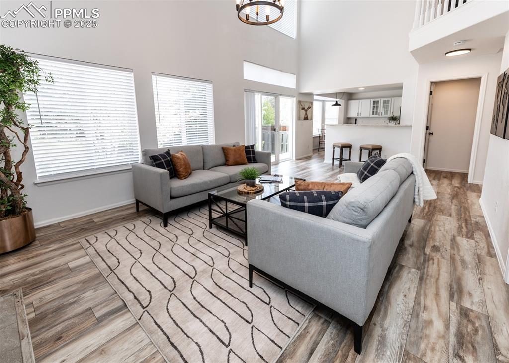Image 18 of 50: Living area with wood finished floors, baseboards, a chandelier, and a high