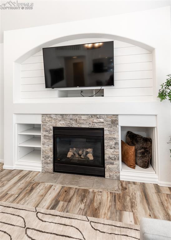 Image 19 of 50: Detailed view of wood finished floors, baseboards, a glass covered fireplac