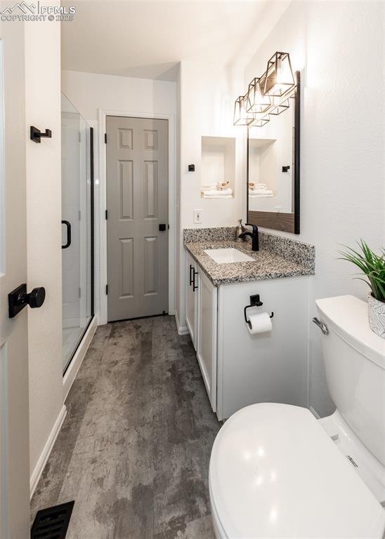 Image 24 of 50: Full bath featuring a shower stall, toilet, vanity, concrete floors, and ba