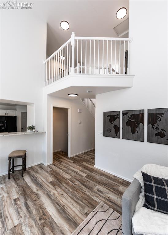 Image 26 of 50: Living room featuring a towering ceiling, wood finished floors, and baseboa