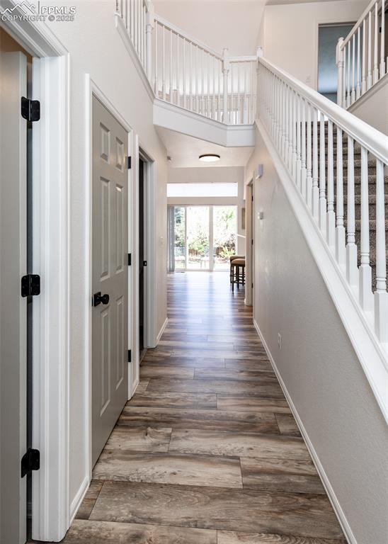 Image 27 of 50: Hall featuring wood finished floors, baseboards, a towering ceiling, and st