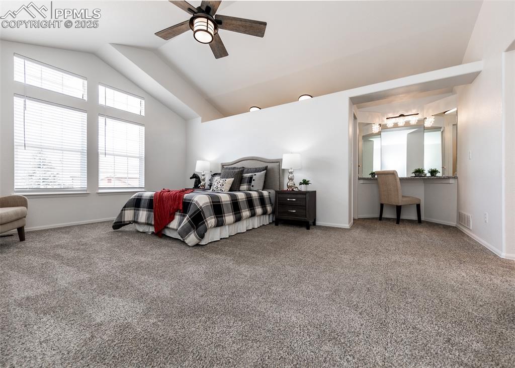 Image 31 of 50: Carpeted bedroom with vaulted ceiling, baseboards, and ceiling fan