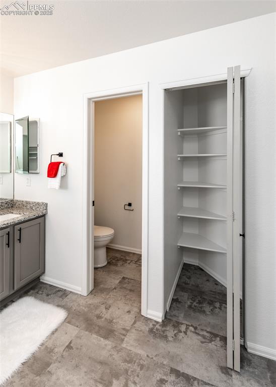 Image 38 of 50: Bathroom with toilet, vanity, and baseboards