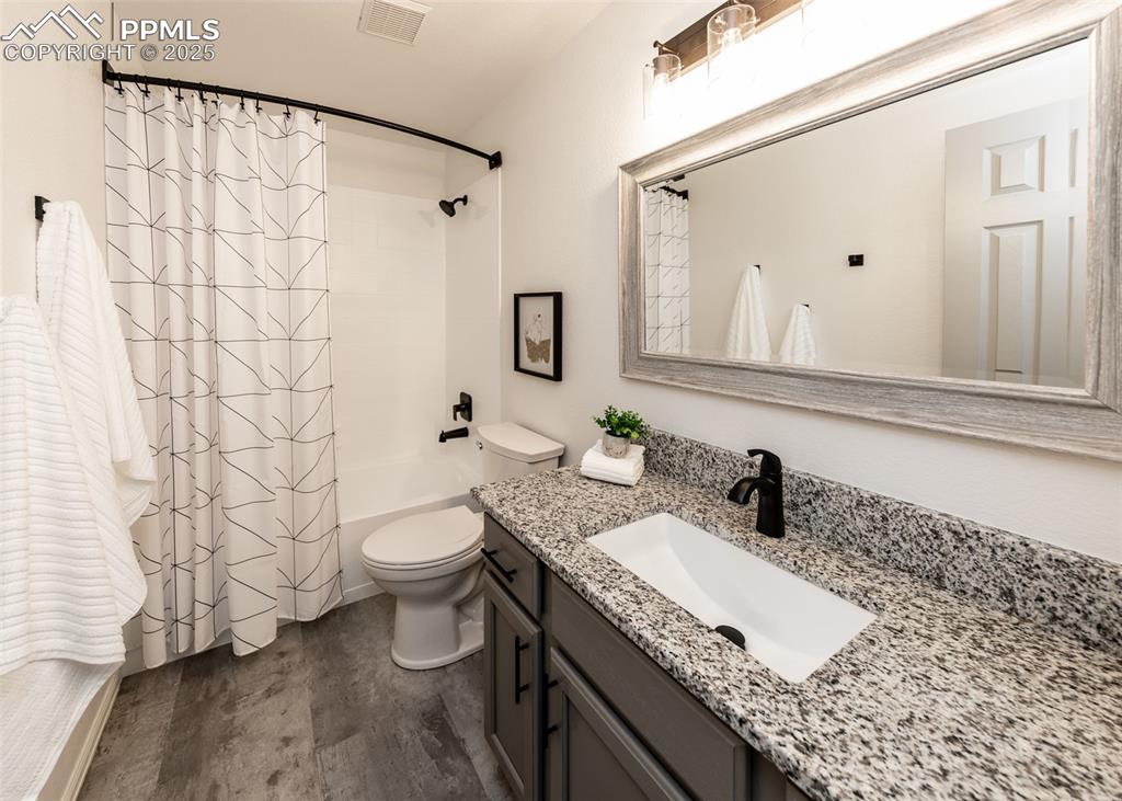 Image 42 of 50: Bathroom with toilet, wood finished floors, shower / bath combo, and vanity