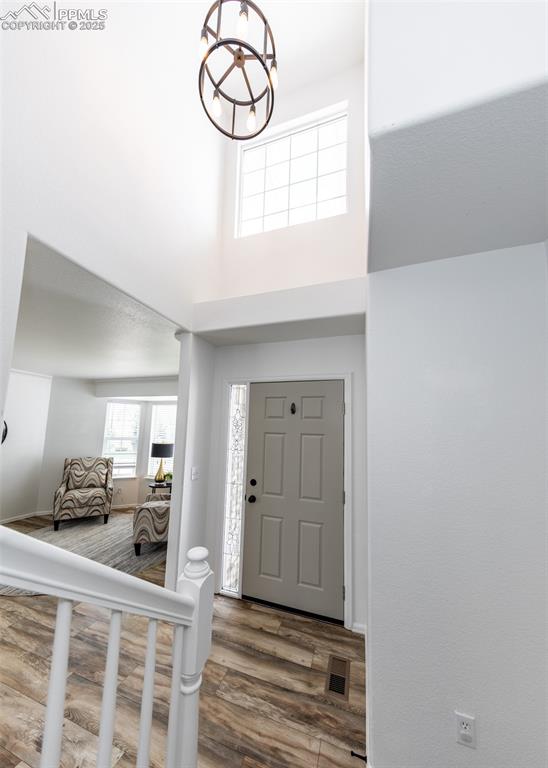 Image 5 of 50: Foyer entrance featuring wood finished floors, a towering ceiling, a chande