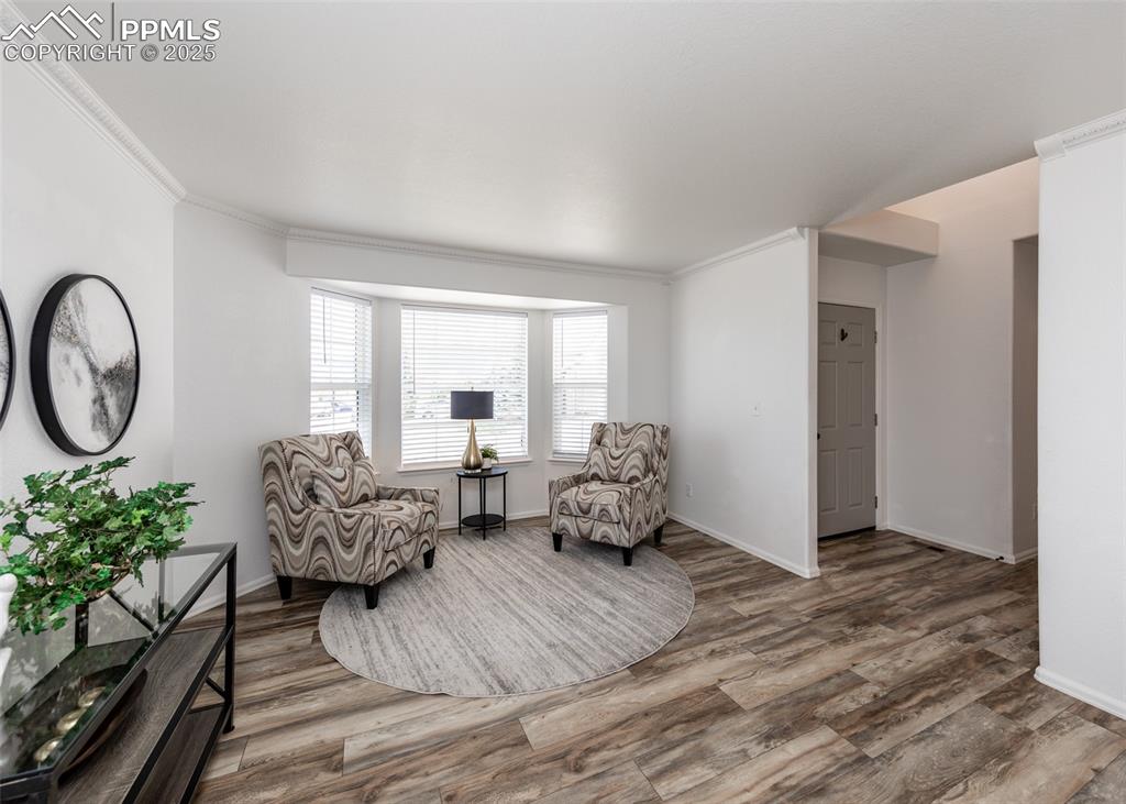 Image 7 of 50: Living area featuring wood finished floors, ornamental molding, and baseboa