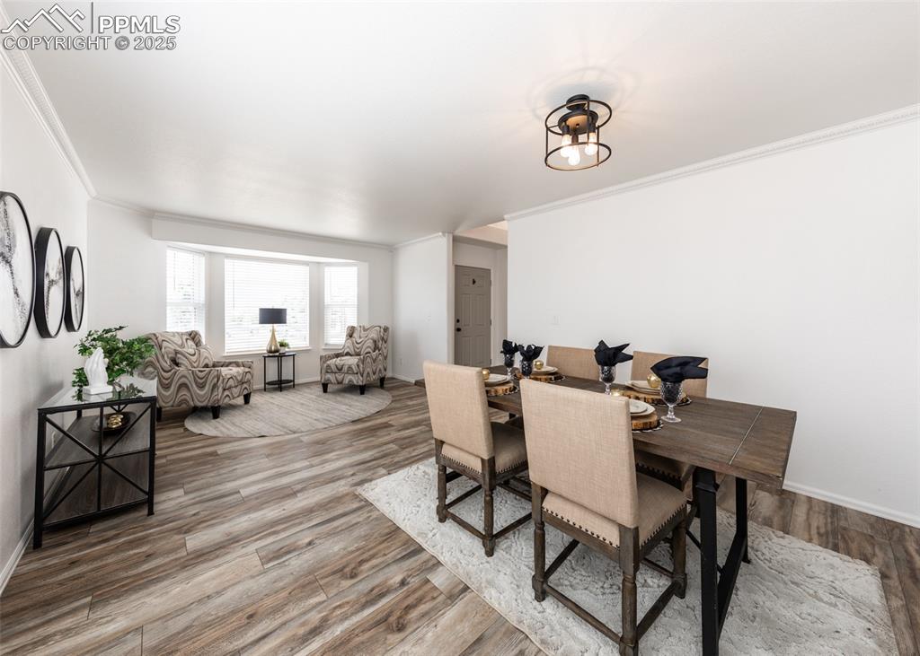Image 9 of 50: Dining space with ornamental molding, wood finished floors, and baseboards