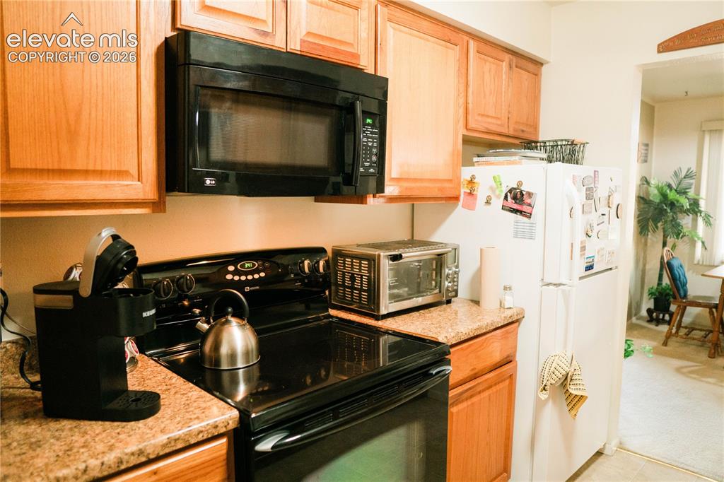 Image 12 of 23: Wood-finish cabinetry paired with a black over-the-range microwave