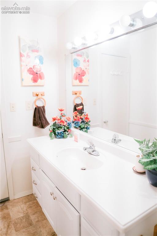 Image 18 of 23: White vanity with integrated sink, chrome faucet, and expansive wall mirror