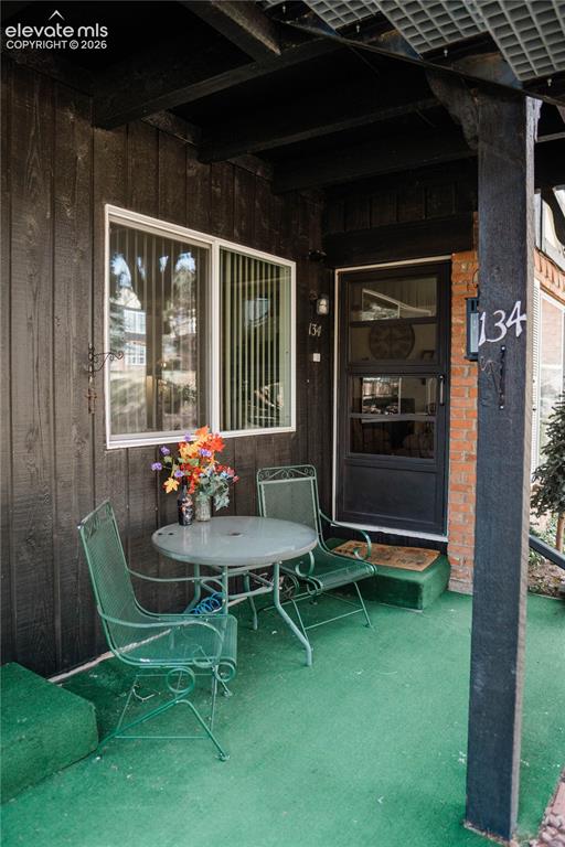 Image 22 of 23: Front porch featuring a textured green floor, dark wood-paneled exterior, a