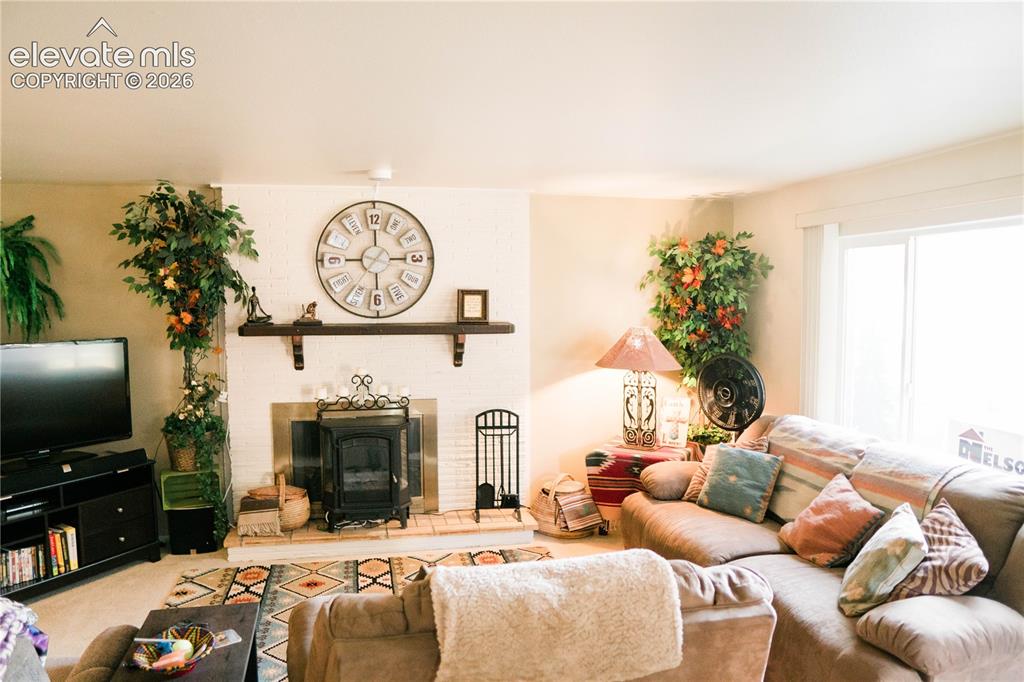 Image 3 of 23: White painted brick fireplace with a wood-burning insert and a wood mantel