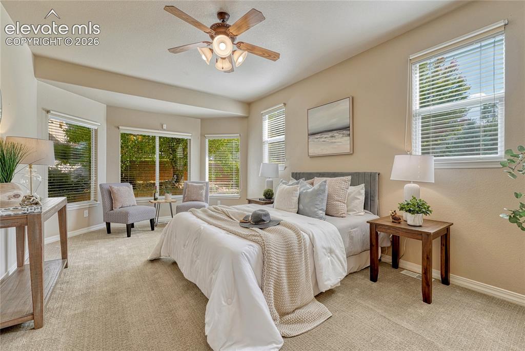 Image 22 of 42: Main level primary bedroom offers natural light, a sitting area...