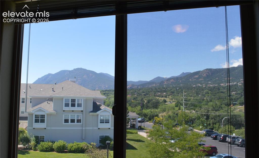 Image 14 of 20: Expansive window framing distant mountains and a lush, tree-lined landscape