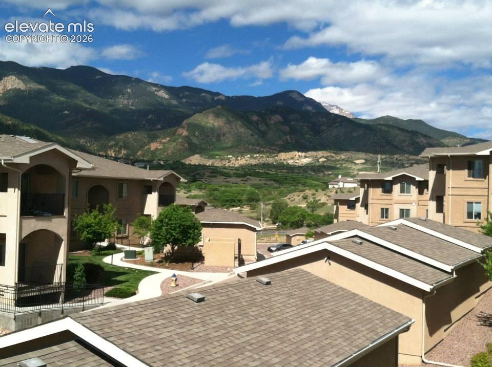 Image 16 of 20: Mountain backdrop, stucco exterior, sloped rooflines, paved pathways, manic