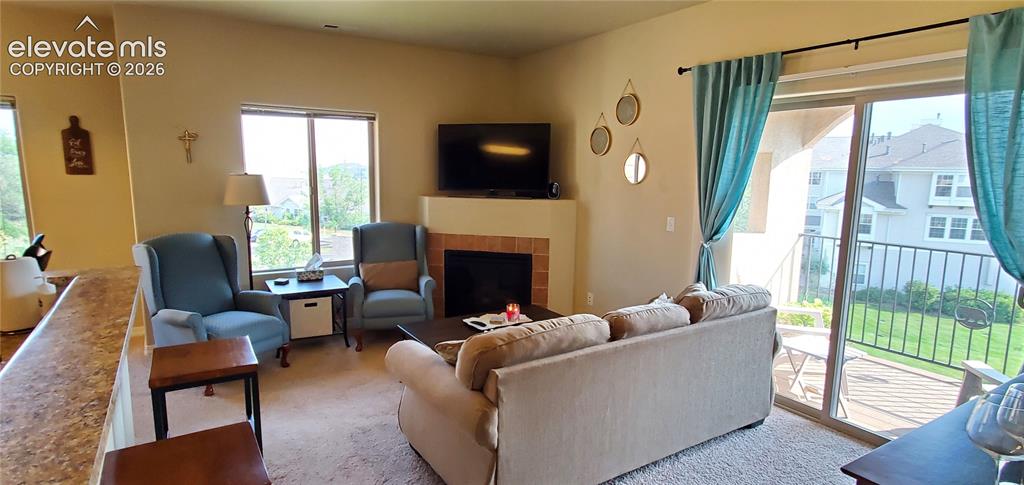 Image 3 of 20: Living area featuring a corner fireplace with brick surround, large window,