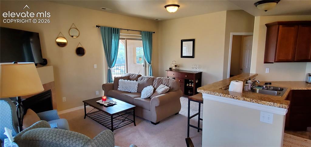 Image 4 of 20: Living area featuring a fireplace, sliding glass door with balcony, and car