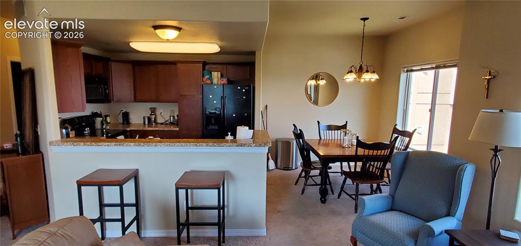 Image 6 of 20: Kitchen with wood cabinetry and black appliances, complemented by a breakfa