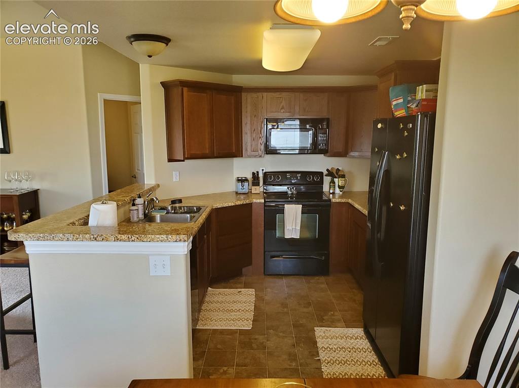 Image 7 of 20: Kitchen featuring wood cabinetry, granite-style countertops, an undermount 